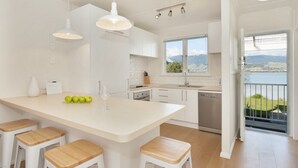 A modern kitchen with a central island, white cabinetry, and a view of mountains through a large window.