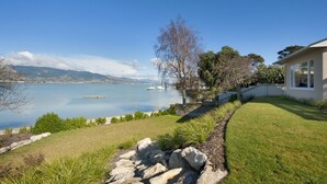 A house with a view of a calm lake and mountains in the background.
