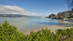 A coastal view with a calm sea, boats, and houses along the shore.
