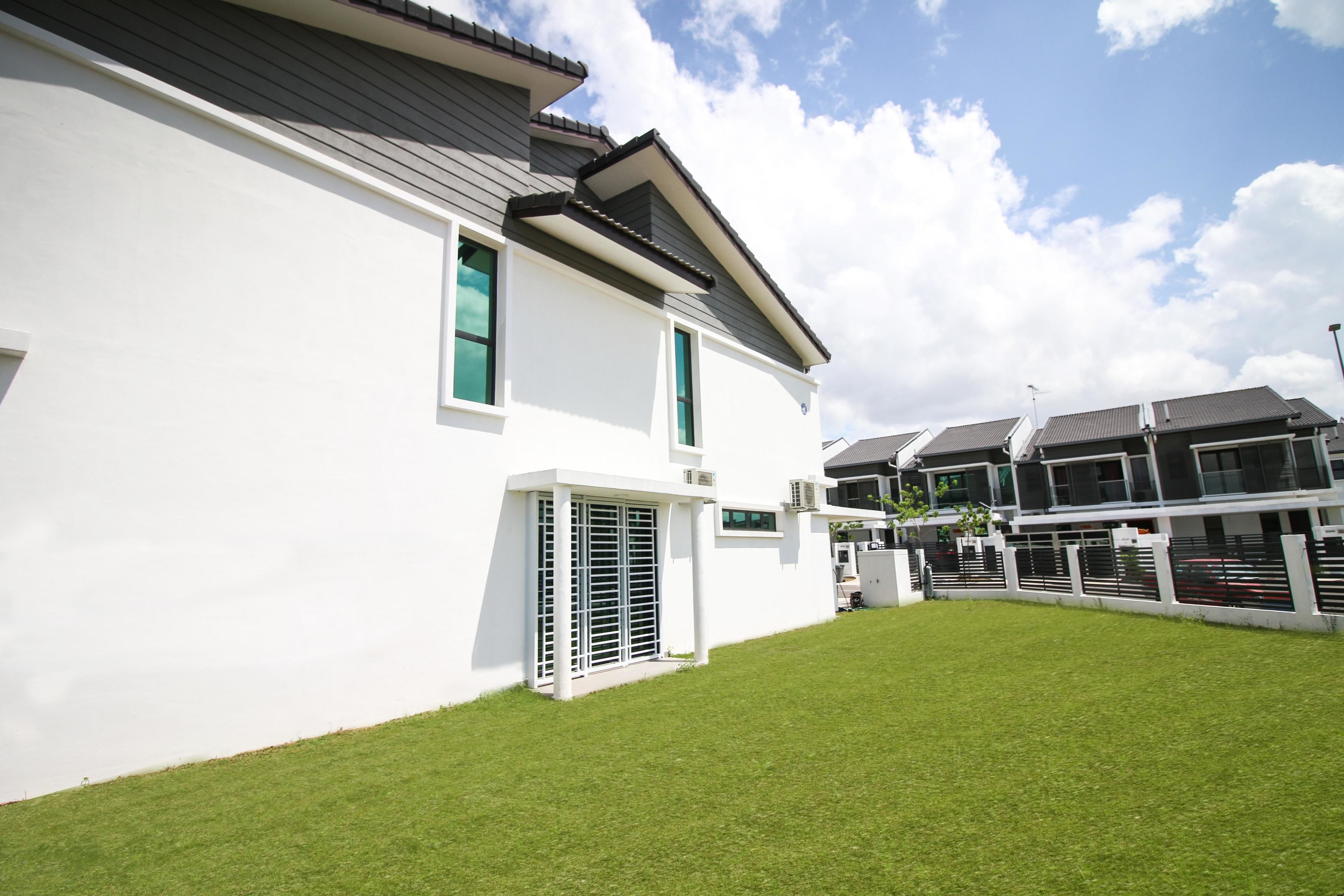 Una casa moderna su due piani, con facciata bianca, tetto spiovente e prato curato.
