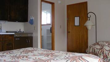 Un dormitorio con cama, armario de madera, espejo y puerta.