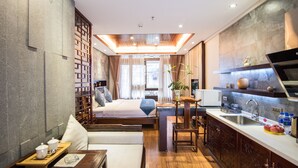 A modern hotel room with a bed, a small kitchenette, a seating area, and a view of the city. - Floral Hotel Dali Honglongjing Junrui (Dali)