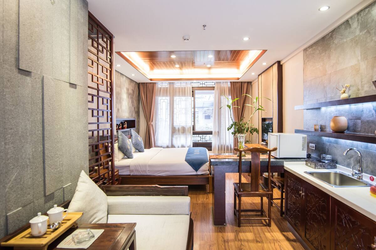 Une chambre d’hôtel moderne comprenant un lit, une petite kitchenette, un coin salon et une vue sur la ville.