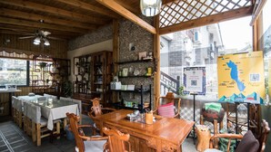 A traditional Japanese inn with wooden interiors, a stone wall, and a view of the cityscape. - Floral Hotel Dali Honglongjing Junrui (Dali)