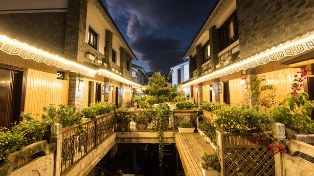 A courtyard with a wooden bridge, stone railings, and potted plants. - Floral Hotel Dali Honglongjing Junrui (Dali)