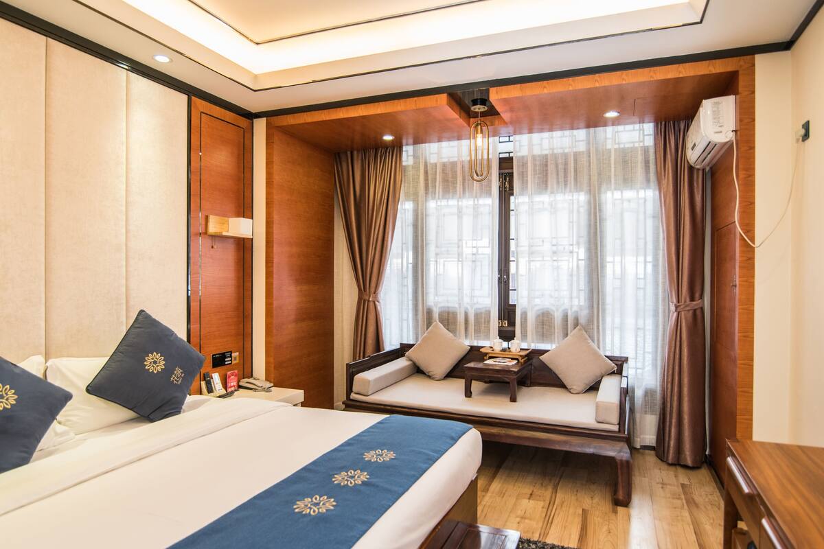 Une chambre d’hôtel avec un lit, un canapé, une petite table et une fenêtre avec des rideaux.