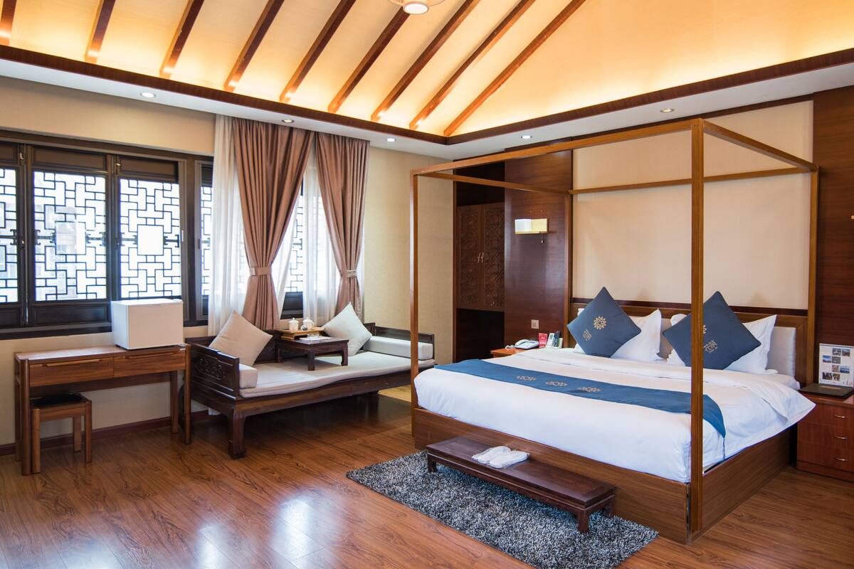 Une chambre d’hôtel moderne dotée d’un lit à baldaquin, d’un bureau et d’un coin salon.