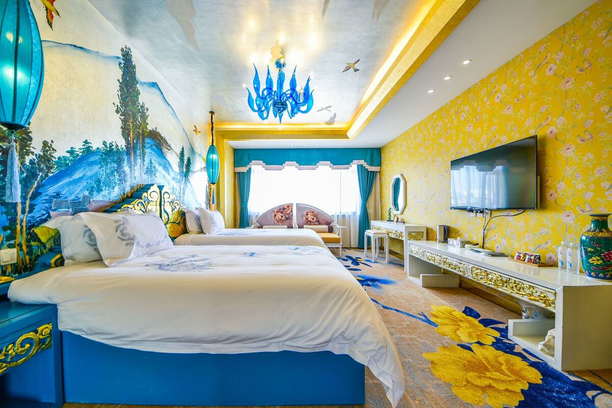 Habitación de hotel con dos camas, televisión, escritorio y un ventanal grande.