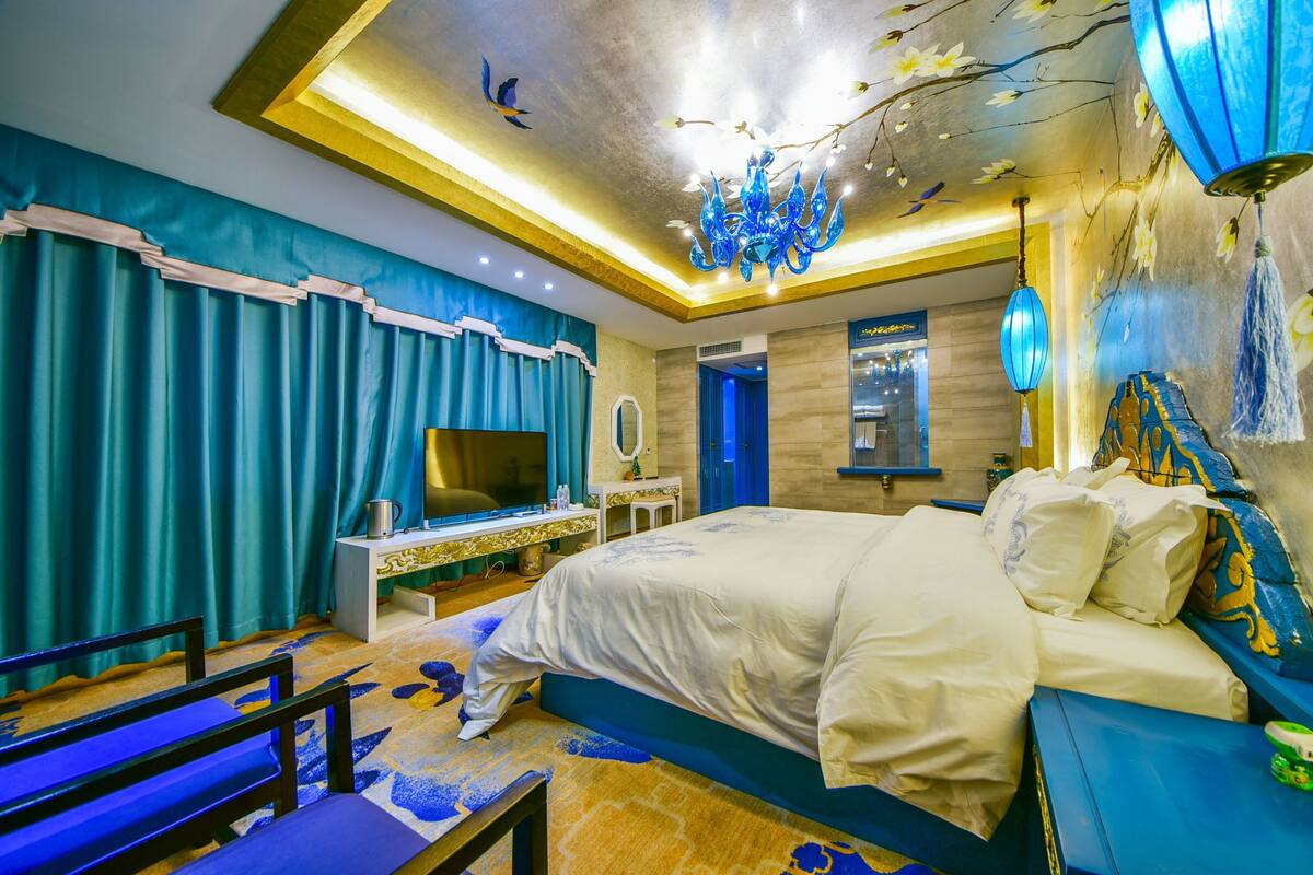 Un dormitorio con una cama grande, televisión, escritorio y silla.