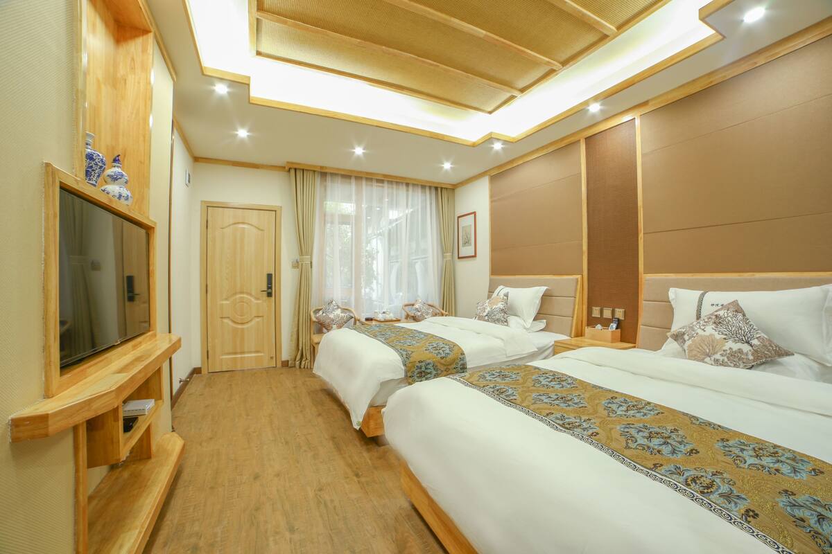 A hotel room with two beds, a TV, and a wooden cabinet.