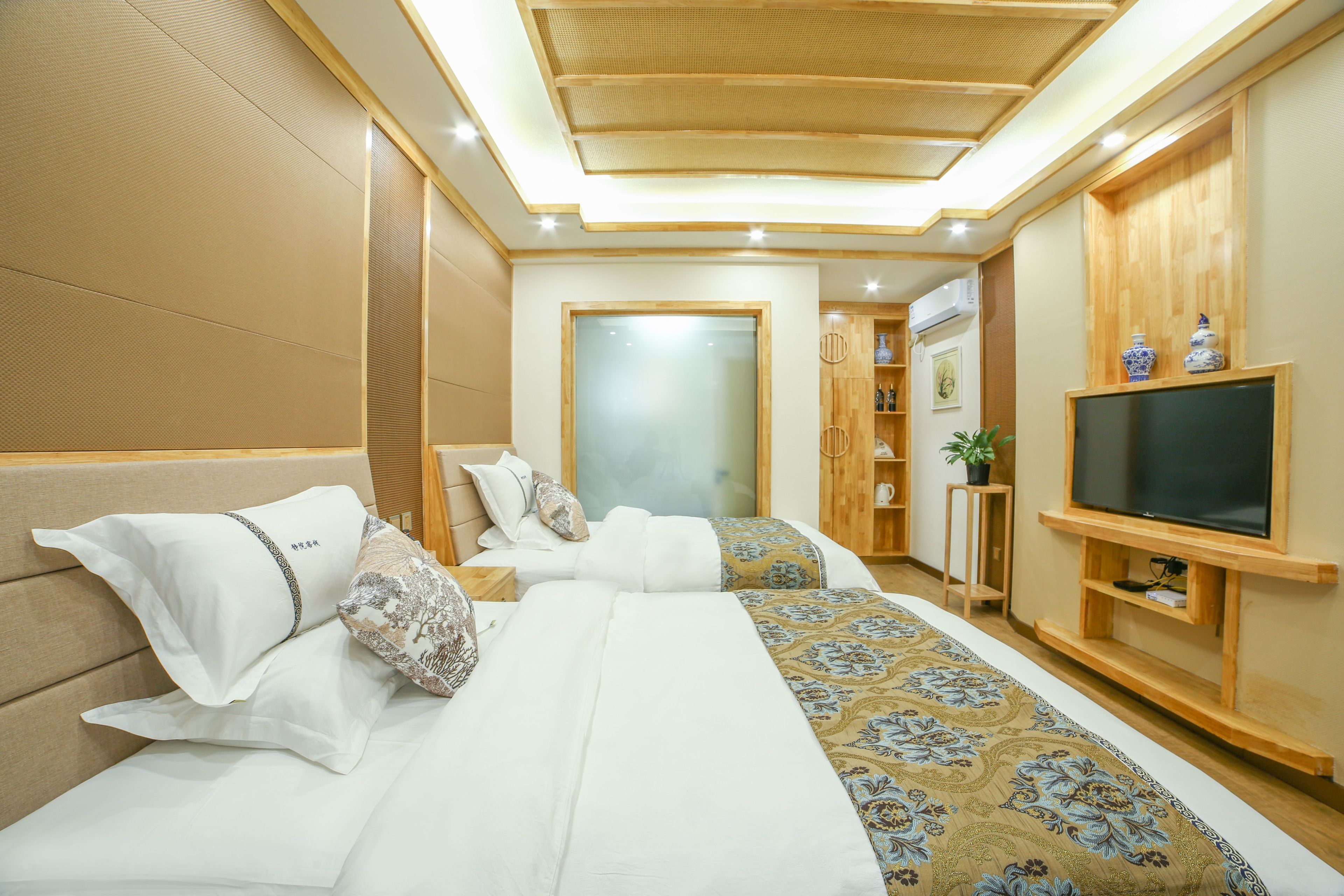 A hotel room with two beds, a television, and a wooden cabinet.