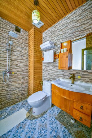 Une salle de bain équipée d’une douche, de toilettes, d’un lavabo et d’un meuble-lavabo en bois.