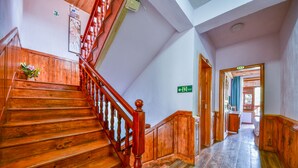 A wooden staircase with a red handrail leading to a landing.