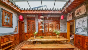 A traditional Chinese room with a wooden table, chairs, and decorative elements like lanterns and paintings.