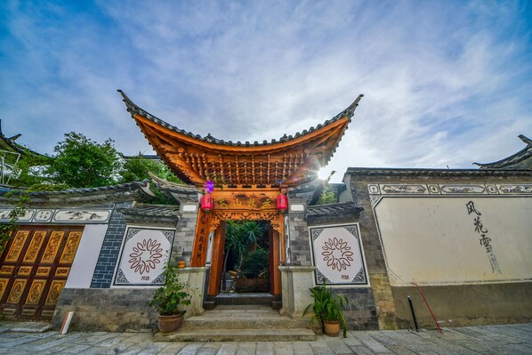 Une porte chinoise traditionnelle, ornée de sculptures complexes et surmontée d’un toit en tuiles.