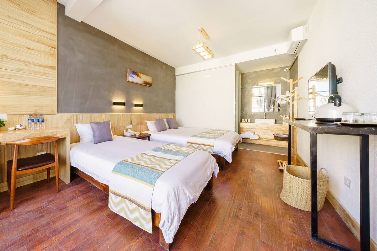 Ein Hotelzimmer mit zwei Betten, einem Schreibtisch, einem Stuhl, einem Spiegel und einem kleinen Tisch.