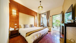 A well-lit bedroom with a large bed, wooden paneling, a bedside table with a lamp, and a view of greenery through the window. - Floral Hotel Dali Yunsheng (Dali)