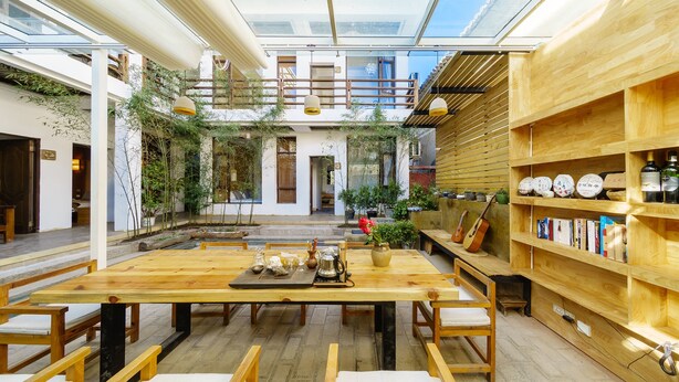 An open-plan living area with a wooden dining table, chairs, and a bookshelf. - Floral Hotel Dali Yunsheng (Dali)