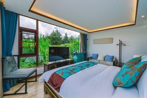 Un dormitorio con una cama grande, televisión, escritorio y una silla.