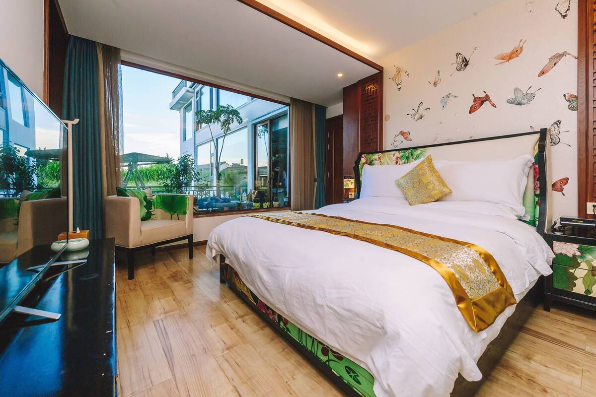 Ein modernes Hotelzimmer mit einem großen Bett, einem Schreibtisch und Blick ins Freie.