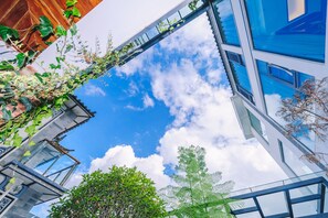 A modern building with a glass facade, a metal staircase, and surrounding greenery. - Floral Hotel Dali Meitingtingyu Boutique (Dali)