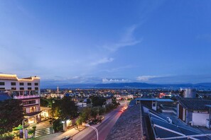 Un paisaje urbano al atardecer con edificios, calles y montañas a lo lejos.