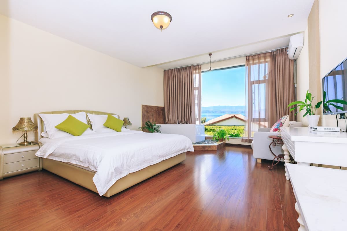 A modern hotel room with a large bed, a desk, and a view of the outdoors.