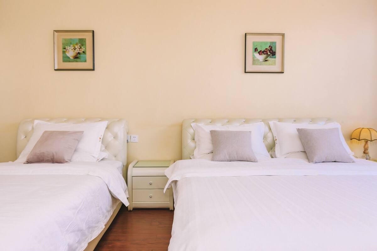 A double room with two beds, each with a nightstand and a lamp.