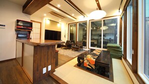 A traditional Japanese-style living room with tatami flooring, a low wooden table, and a sofa. - Kyotoya Junnya (Kyoto)