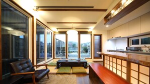 A modern kitchen with a wooden countertop, built-in appliances, and large windows offering a view of the outdoors. - Kyotoya Junnya (Kyoto)