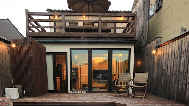 A modern house with a wooden deck, a covered patio, and a gravel garden. - Kyotoya Junnya (Kyoto)