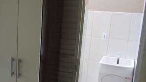 A room with a wardrobe, a sliding door leading to a bathroom with a sink and mirror.