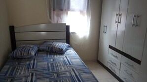 A bedroom with a bed, a wardrobe, and a window with curtains.