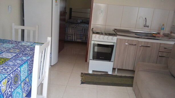 A compact kitchen with a refrigerator, oven, and sink. There is a dining area with a table and chairs.