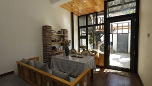 Een gezellig eetgedeelte met een houten bank, een tafel met geruit tafelkleed en een boekenplank van baksteen.