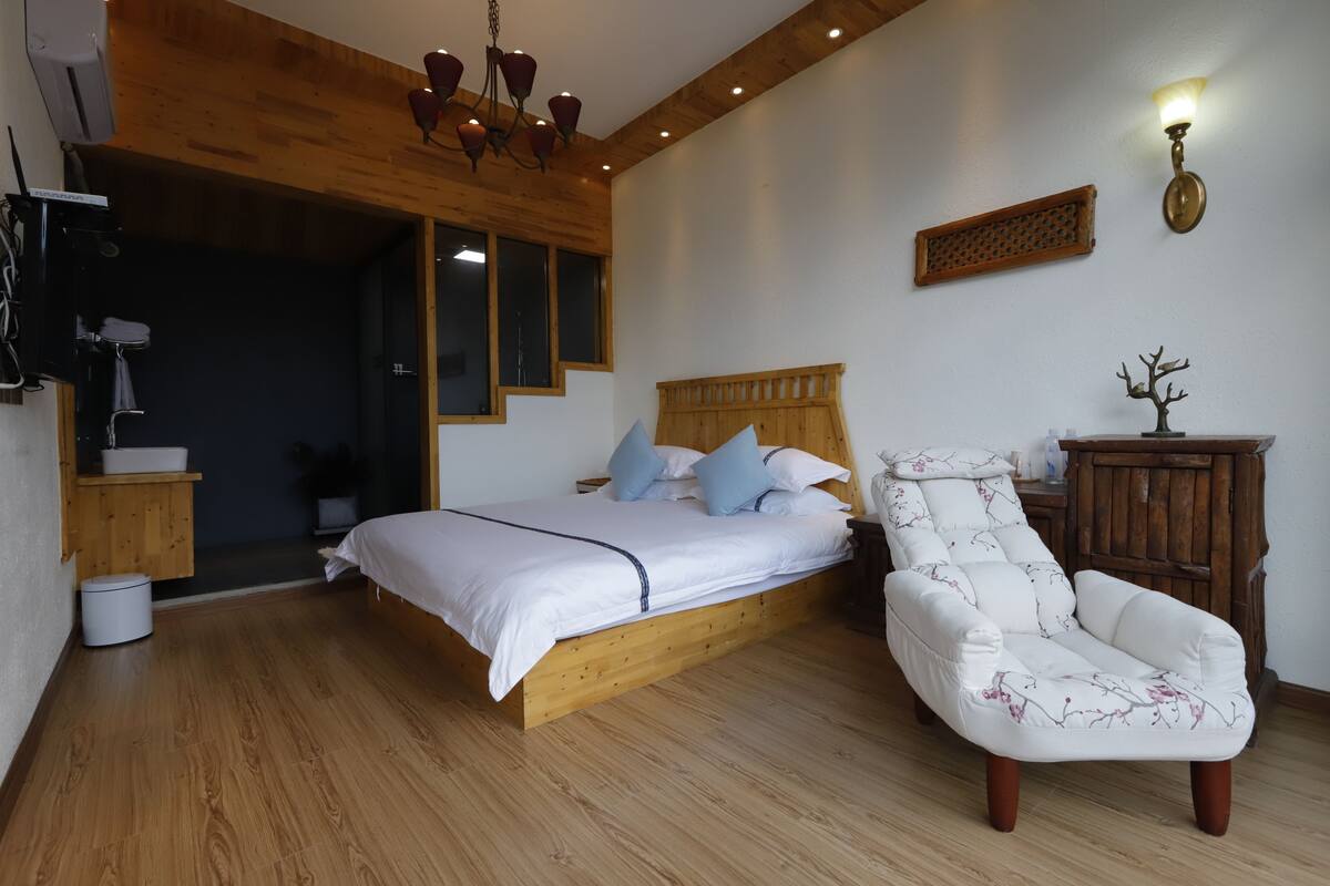 A bedroom with a wooden bed, a white chair, and a wooden cabinet.