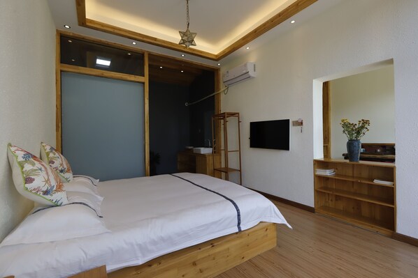 A bedroom with a wooden bed, a TV, a mirror, and a wooden shelf with a vase.