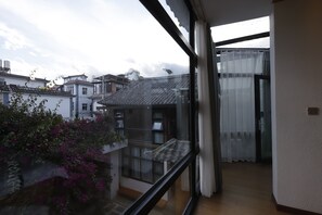 A view from a balcony with traditional architecture, a glass door, and a balcony with a table and chairs.
