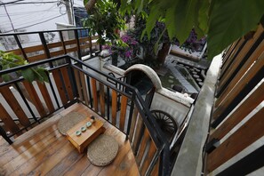 A wooden deck with a table and chairs, a stone pathway, and a view of a garden with pink flowers.