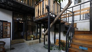 Een modern gebouw met een houten trap, een kleine tuin met plantenpotten en een traditioneel Chinees raamontwerp.