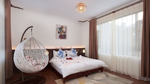 Une chambre à coucher avec un lit, un fauteuil suspendu, une œuvre d’art murale et une grande fenêtre avec des rideaux.