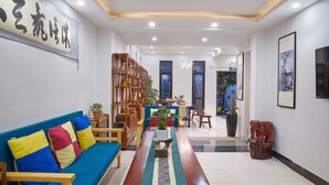A reception area with a blue sofa, wooden chairs, a coffee table, and a bookshelf.