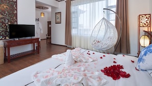 A hotel room with a bed, a television, a hanging chair, and a decorative wall.