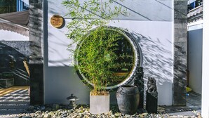 Ein traditioneller japanischer Garten mit einem runden Teich, Bambuspflanzen und Steinleuchten.