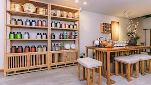 Ein traditionelles Teehaus-Interieur mit Holzböden und Regalen, auf denen verschiedene Teeblechdosen ausgestellt sind, sowie ein Holztisch mit Hockern.