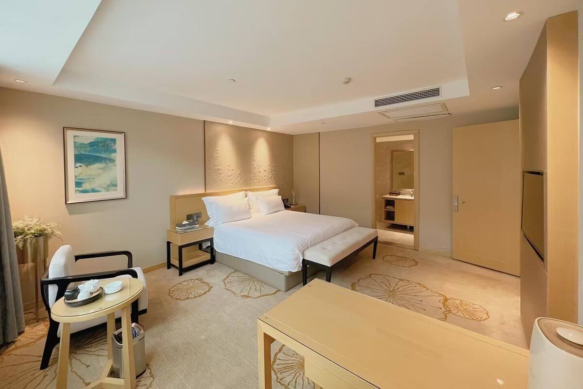 Een moderne hotelkamer met een groot bed, nachtkastjes, een bureau en een stoel.