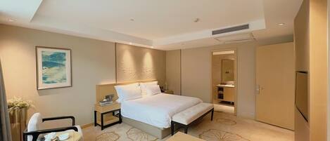 A modern hotel room with a large bed, bedside tables, a desk, and a chair.