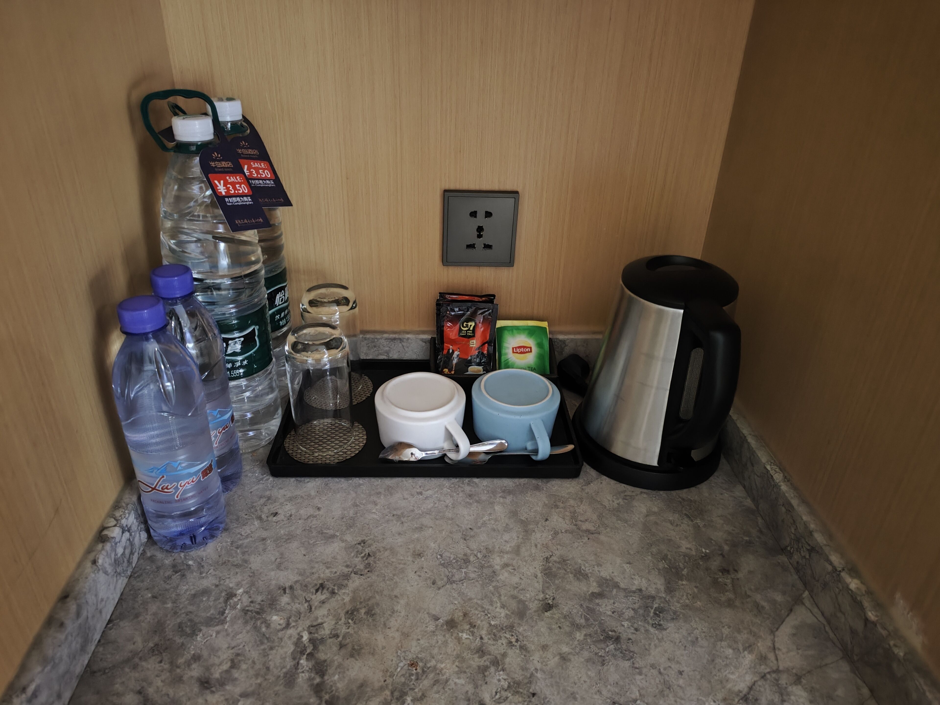 Un angolo cottura con una macchina per caffè, due tazze, un bollitore, una teiera e bottiglie d'acqua.