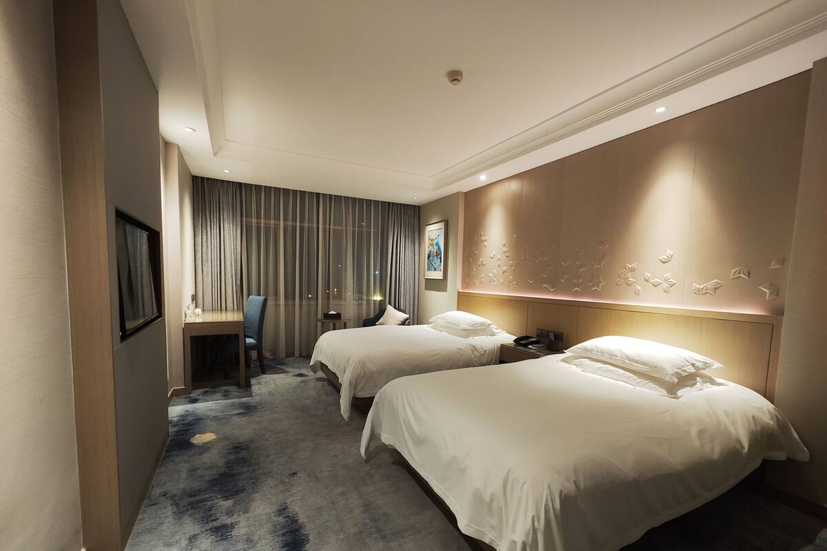 Een hotelkamer met twee bedden, een bureau en een stoel.