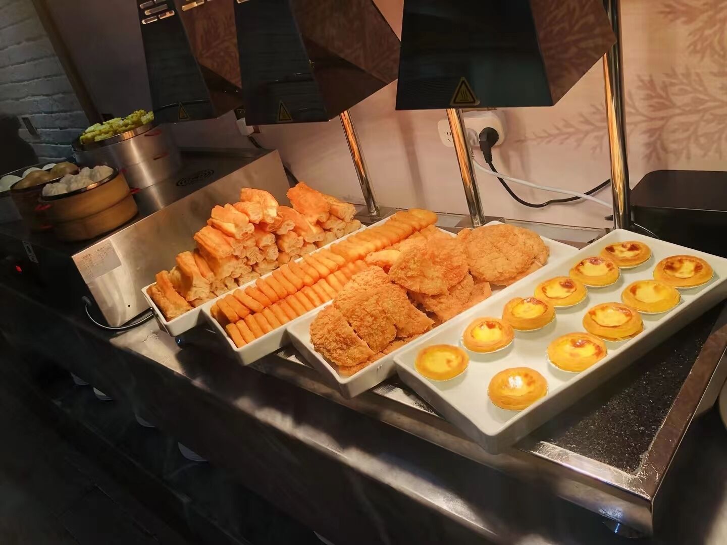 Un bufé con diversos platos, incluyendo opciones empanizadas, bollería y una variedad de acompañamientos.